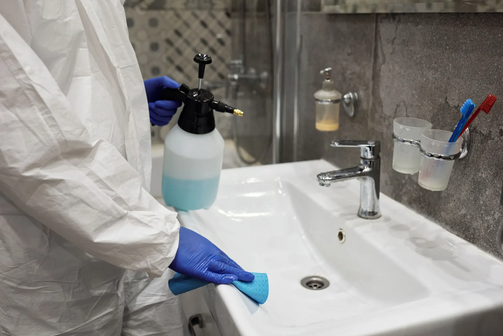 Professional cleaner sanitising a bathroom sink