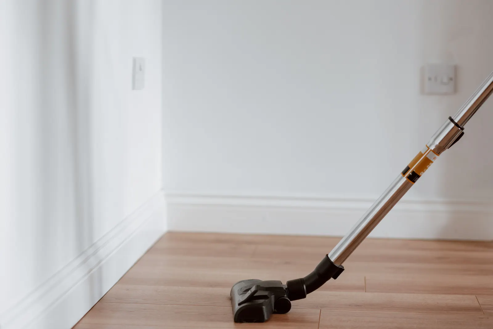 Vacuum cleaner working along a wooden floor edge